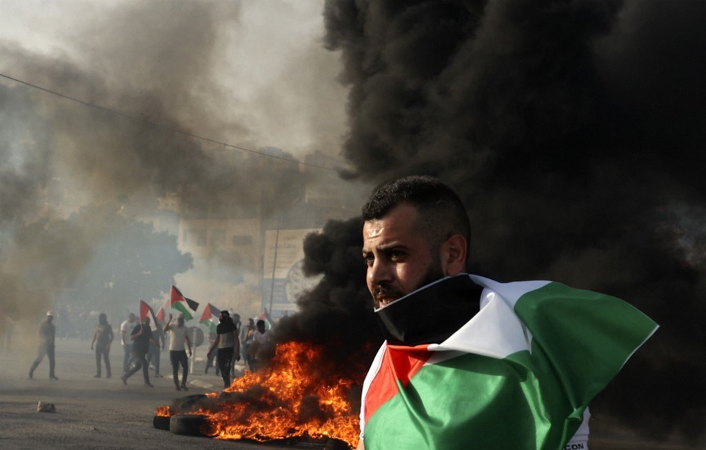 متظاهر يلتف بالعلم الفلسطيني عند حاجز حوارة بالقرب من نابلس في الضفة الغربية المحتلة