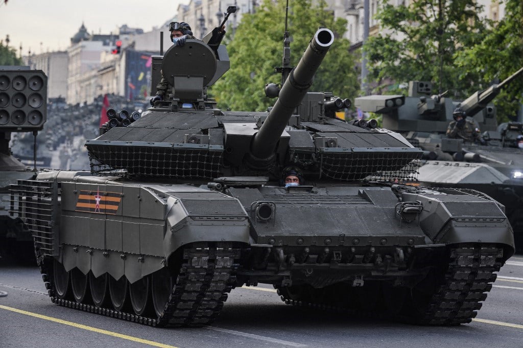 جنود من الجيش الروسي يرتدون أقنعة واقية يركبون دبابة T-90