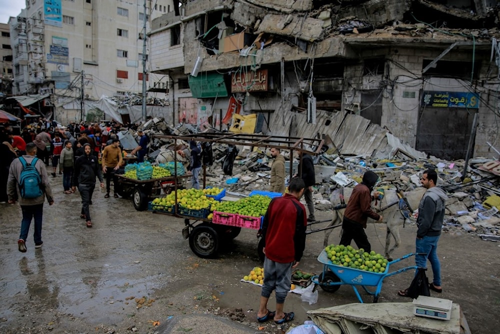 فلسطينيون يبيعون الخضار أمام مبنى مدمر بغارة إسرائيلية في مدينة غزة - 27 تشرين الثاني/نوفمبر 2023 (أ ف ب)