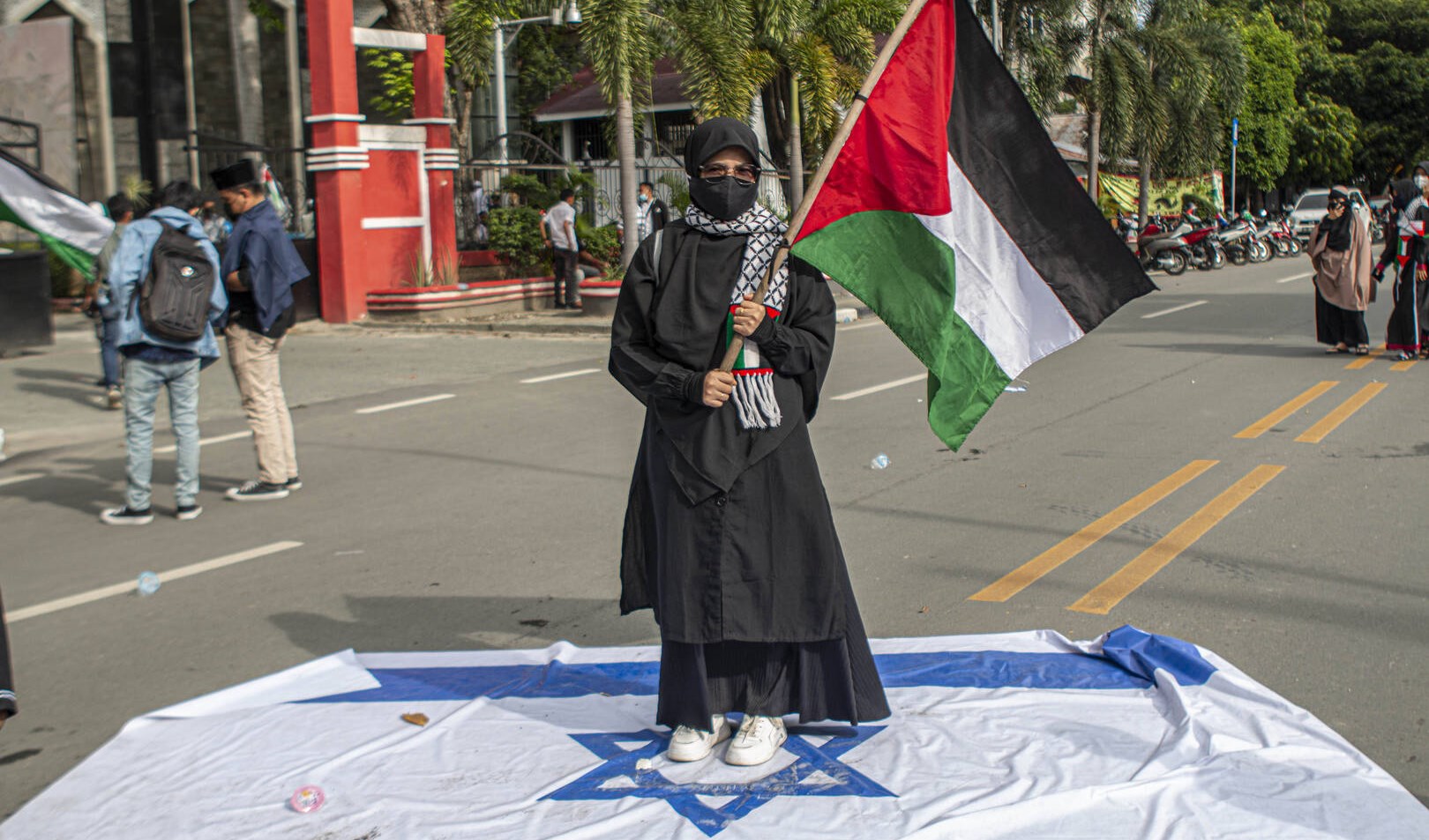 امرأة إندونيسية تحمل العلم الفلسطيني وتدوس على علم الاحتلال الإسرائيلي (أرشيف)