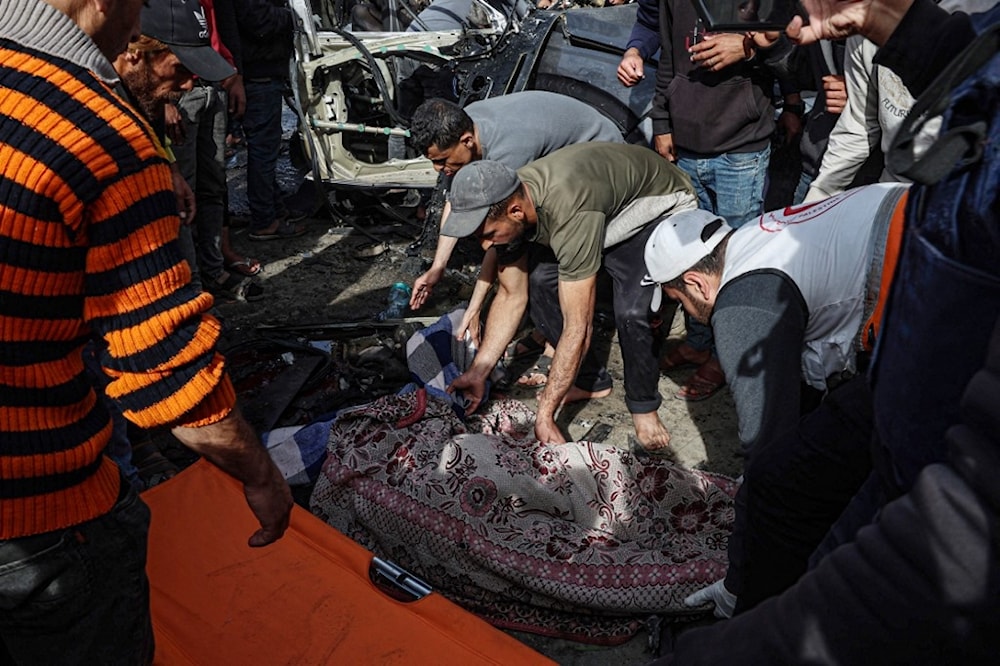 فلسطينيون يغطون جثمان شهيد ارتقى في إثر القصف الإسرائيلي على رفح، جنوبي قطاع غزة (أ ف ب)