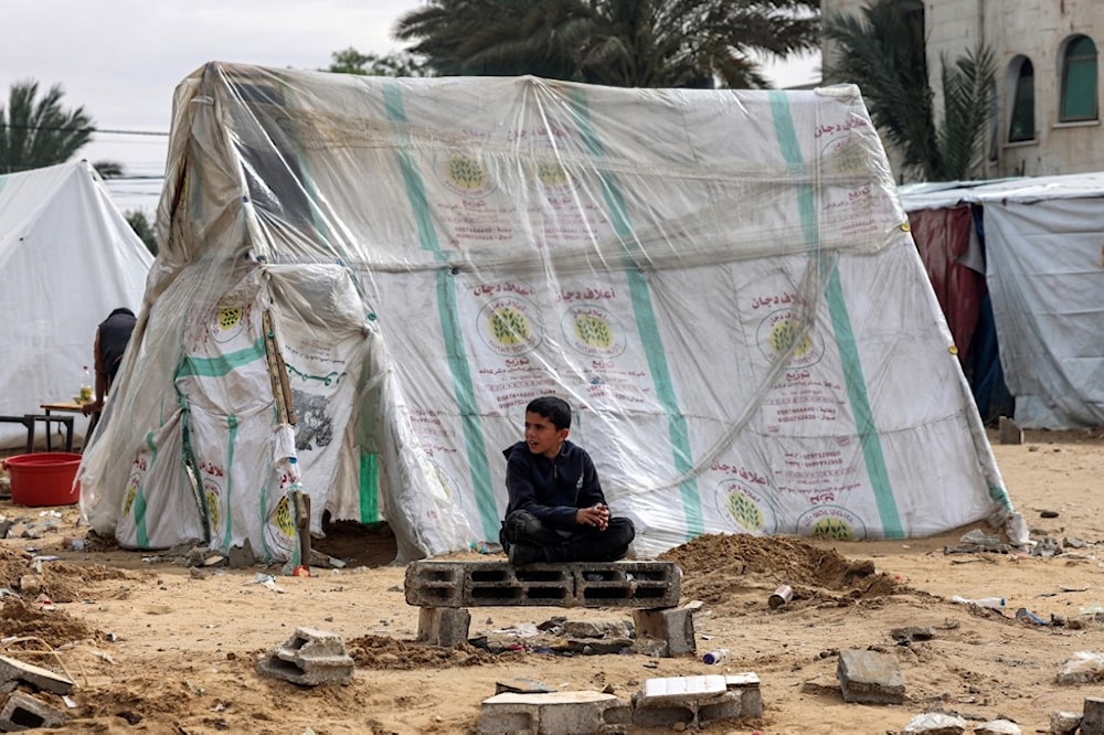 طفل فلسطيني يجلس قرب خيمة للنازحين في رفح، جنوبي قطاع غزة، بعد أن هجّر الاحتلال أهالي القطاع (أرشيف - أ ف ب)