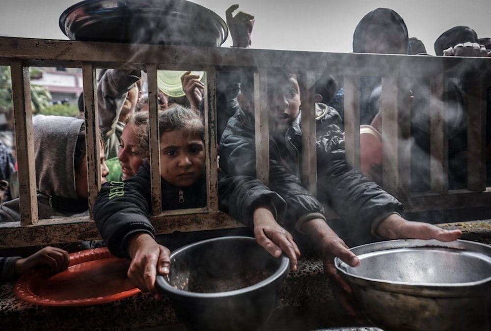 أطفال فلسطينيون يتجمعون للحصول على الطعام في مدرسة حكومية في رفح جنوبي قطاع غزة - 19 شباط/فبراير 2024 (أ ف ب)