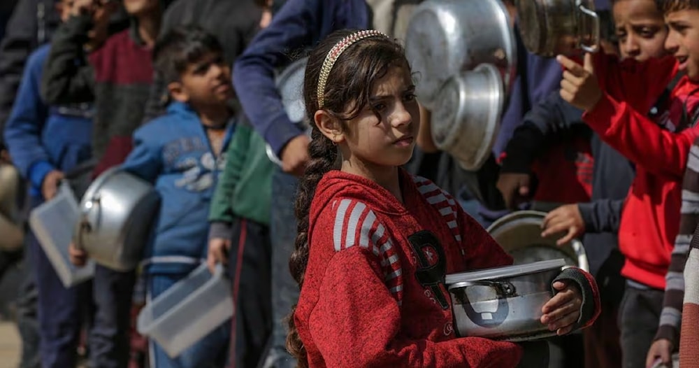 أطفال فلسطينيون يصطفون حاملين الأواني والحاويات في انتظار الحصول على الغذاء في دير البلح جنوبي قطاع غزة