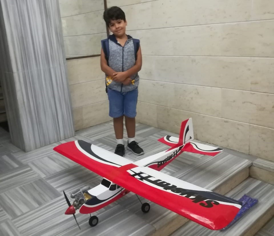 الطفل التنير مع طائرة الأولى التي صنعها بيديه