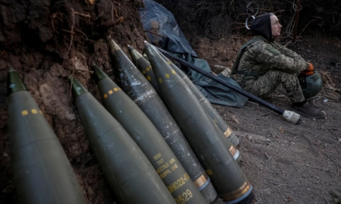 جندي أوكراني يجلس إلى جانب قذائف من المساعدات العسكرية الغربية لأوكرانيا (رويترز)