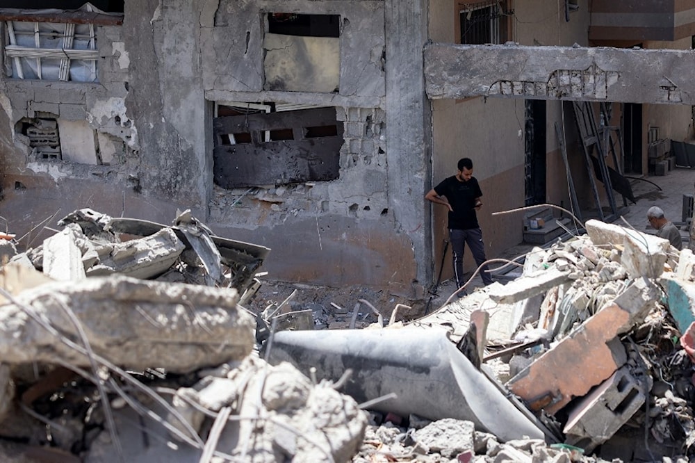 فلسطينيان وسط الركام الذي أحدثه القصف الإسرائيلي الذي استهدف مخيم النصيرات، وسط قطاع غزة (أرشيفية - أ ف ب)