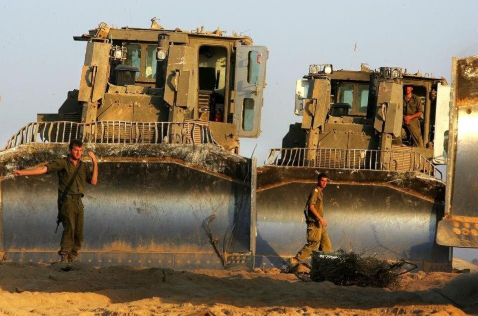 جنود إسرائيليون يقفون أمام جرافات من نوع 