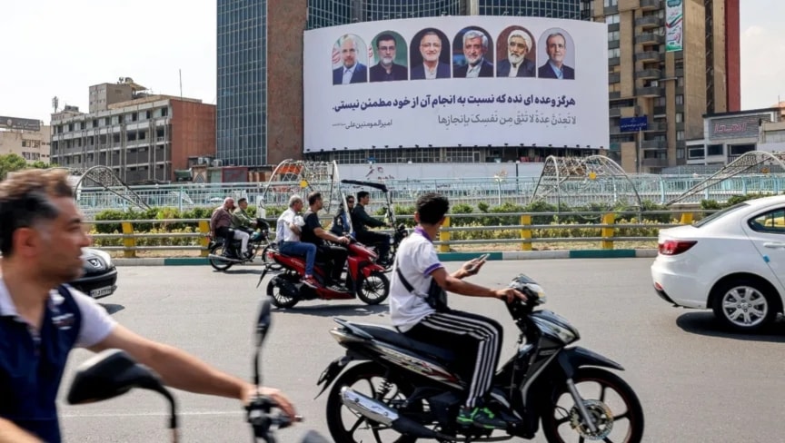 مركبات تمر أمام لوحة إعلانية تعرض صور مرشحي انتخابات الرئاسة الإيرانية في ميدان 