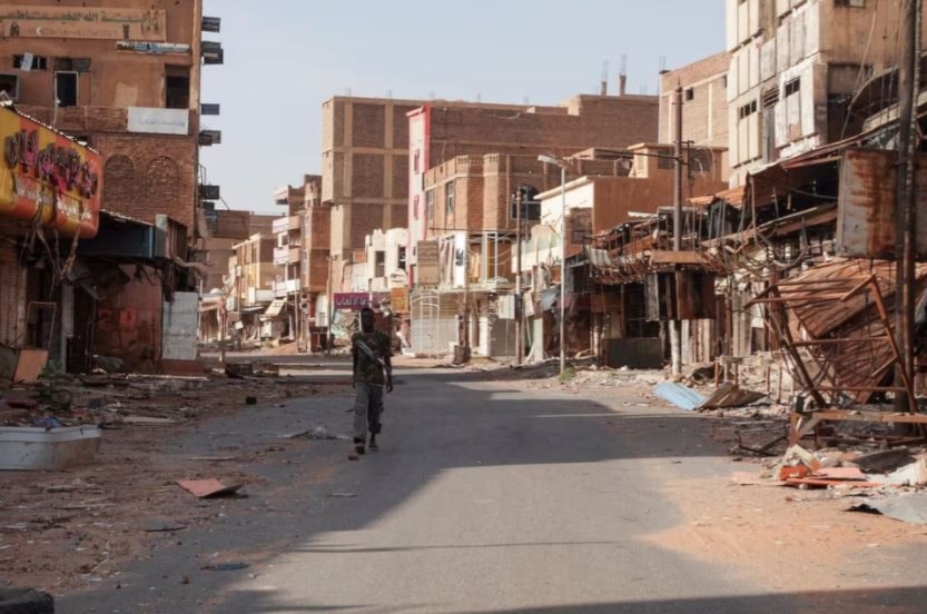 أحد أفراد القوات السودانية يتجول بين المباني المتضررة بعد عام من الحرب مع الدعم السريع في أم درمان 7 نيسان/أبريل 2024 