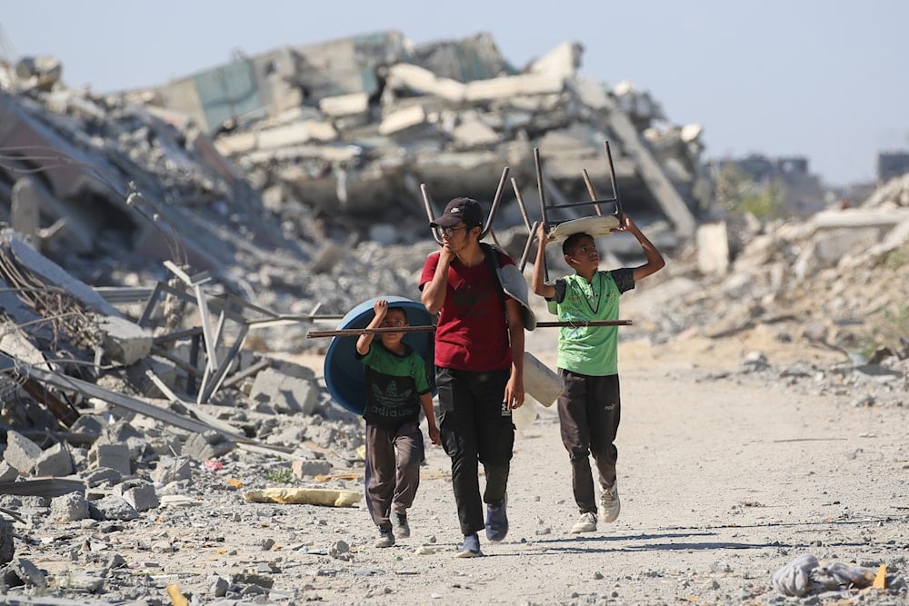 فلسطينيون يحملون كراسي وحوضاً بلاستيكياً عائدين إلى منازلهم في منطقة الزهراء شمال مخيم النصيرات للاجئين في وسط قطاع غزة (أ ف ب)