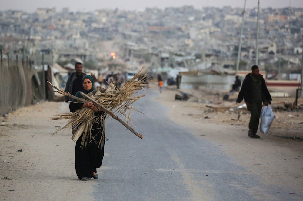 امرأة فلسطينية تحمل الحطب لإشعال النار في خان يونس جنوب قطاع غزة (أ ف ب)
