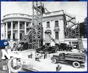 في هذه الصورة بالأبيض والأسود، يظهر الرواق الجنوبي للبيت الأبيض مغطى بالسقالات ومحاط بشاحنات البناء التي تعود إلى أربعينيات القرن العشرين وعمال يحملون عربات يدوية. في هذه الصورة بالأبيض والأسود، يظهر الرواق الجنوبي للبيت الأبيض مغطى بالسقالات ومحاط بشاحنات البناء التي تعود إلى أربعينيات القرن العشرين وعمال يحملون عربات يدوية.