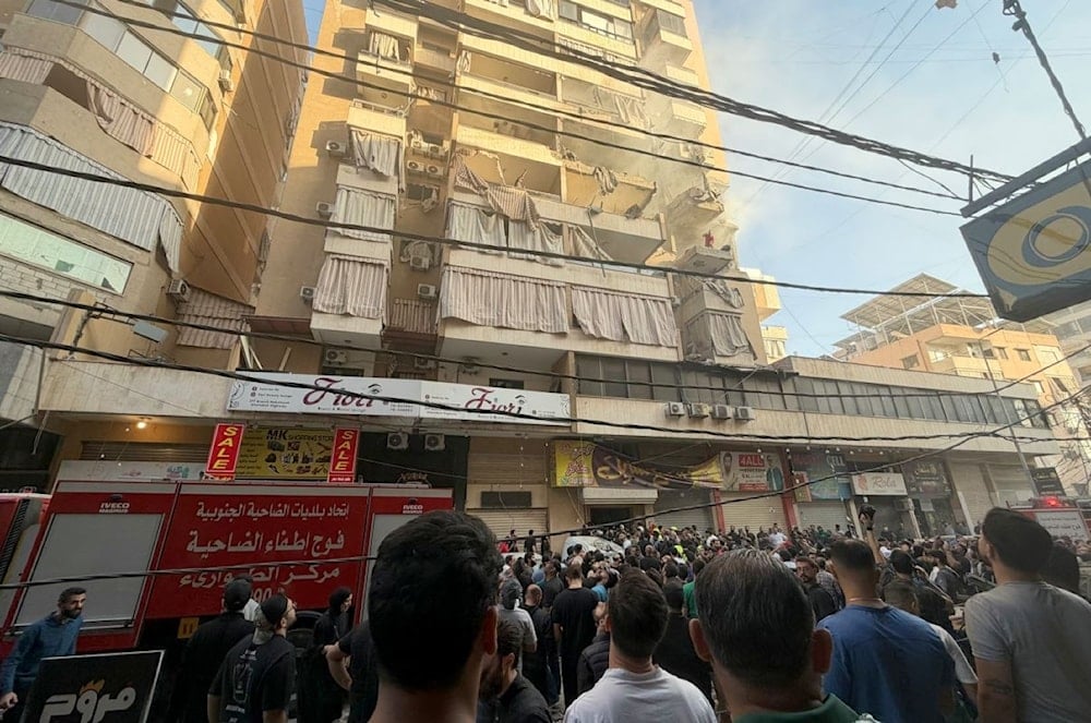 تجمع الناس في محيط المبنى السكني الذي استهدفه عدوان الاحتلال في الضاحية الجنوبية لبيروت - 23 تشرين الثاني/نوفمبر 2025 (أ ف ب)