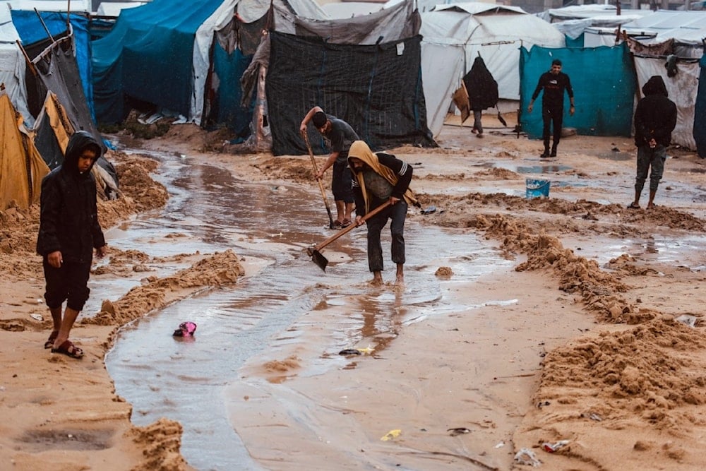 فلسطينيون يحفرون قنوات في الرمال لتوجيه مياه الأمطار في دير البلح وسط قطاع غزة 25 تشرين الثاني/نوفمبر 2025 (أ ف ب)