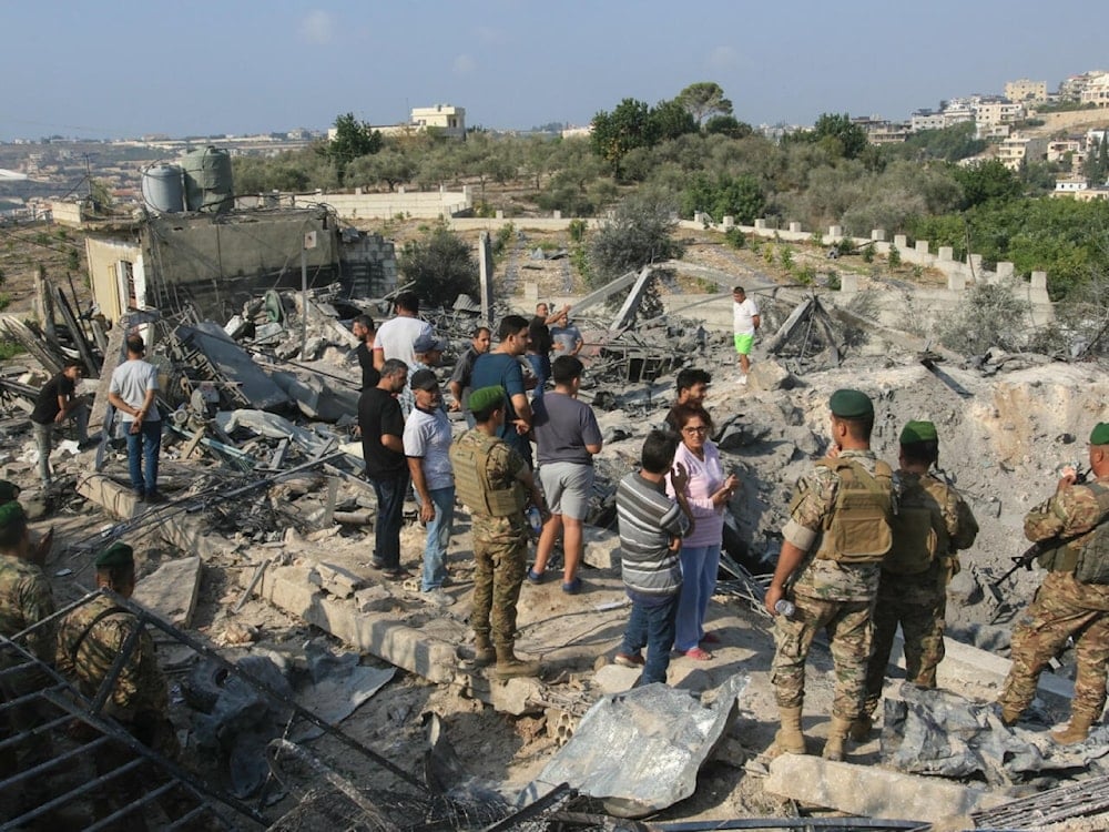 جنود من الجيش اللبناني يقفون إلى جانب المدنيين وسط ركام غارة إسرائيلية استهدفت قرية طورة في جنوب لبنان، في 6 تشرين الثاني/نوفمبر 2025 (أ ف ب)