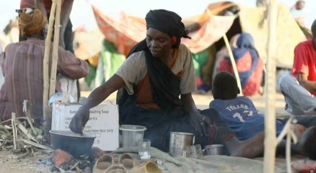 امرأة سودانية نازحة تُحضّر الطعام بعد فرارهم من مدينة الفاشر بدارفور في السودان (رويترز)