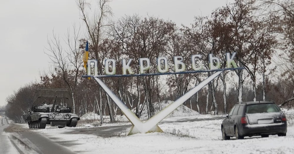 دبابة أوكرانية وسيارة متوقفتان بالقرب من لافتة طريق مكتوب عليها بوكروفسك وسط الهجوم الروسي (رويترز)