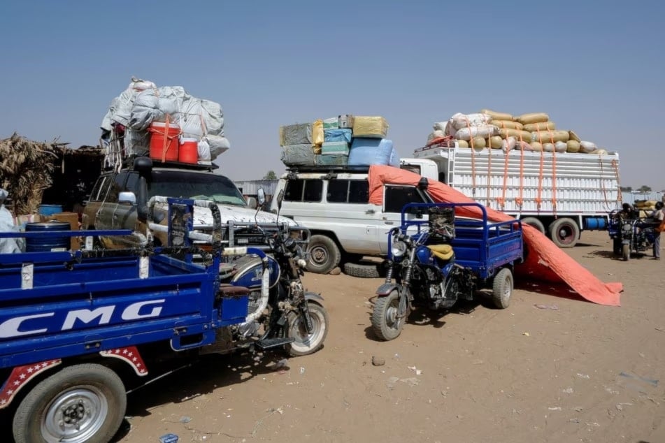 شاحنات تنقل نازحين من الفاشر في مخيم في الضبة في السودان (رويترز)