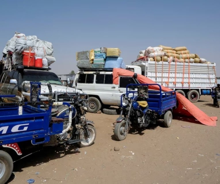 شاحنات تنقل نازحين من الفاشر في مخيم في الضبة في السودان (رويترز)