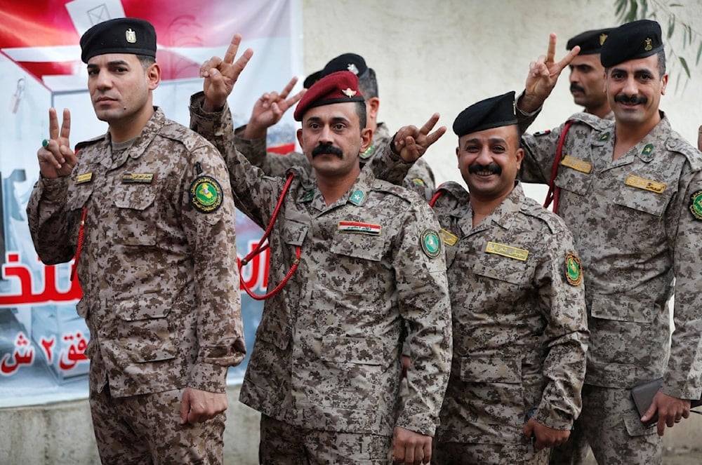 جنود عراقيون يلوحون بعلامة النصر قبل الإدلاء بأصواتهم في مركز اقتراع، خلال يوم التصويت الخاص في العاصمة بغداد (أ ف ب)