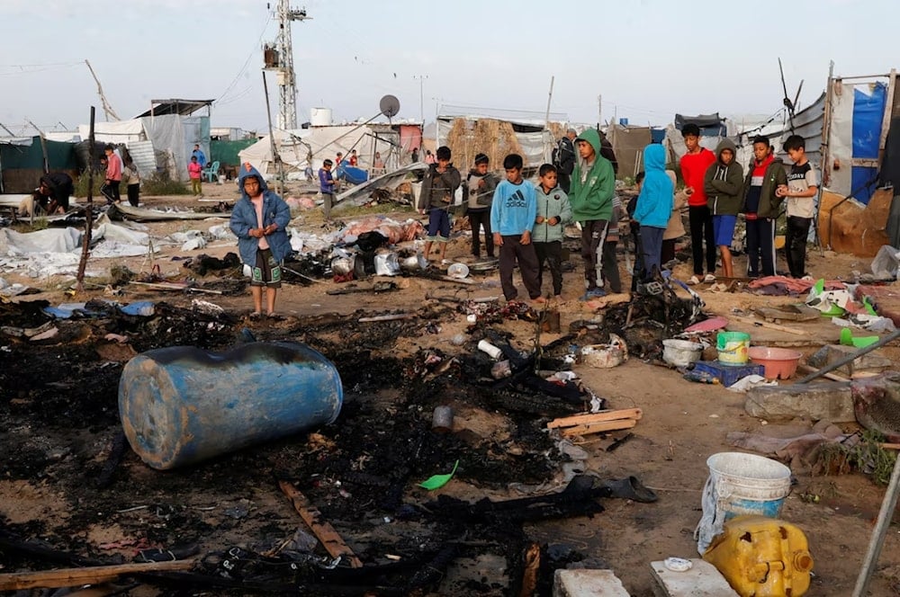 فلسطينيون يتفقدون موقع غارة إسرائيلية على مخيم للنازحين في منطقة المواصي في خان يونس جنوب قطاع غزة (رويترز)