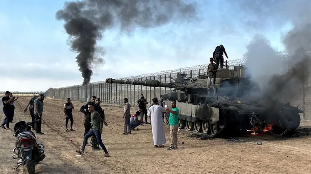 فلسطينيون يحتفلون على ظهر دبابة إسرائيلية عند الجدار العازل في قطاع غزة يوم الـ7 من تشرين الأول/أكتوبر 2023 