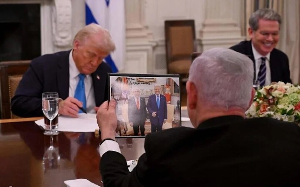نتنياهو ينظر إلى صورة تجمعه مع الرئيس الأميركي