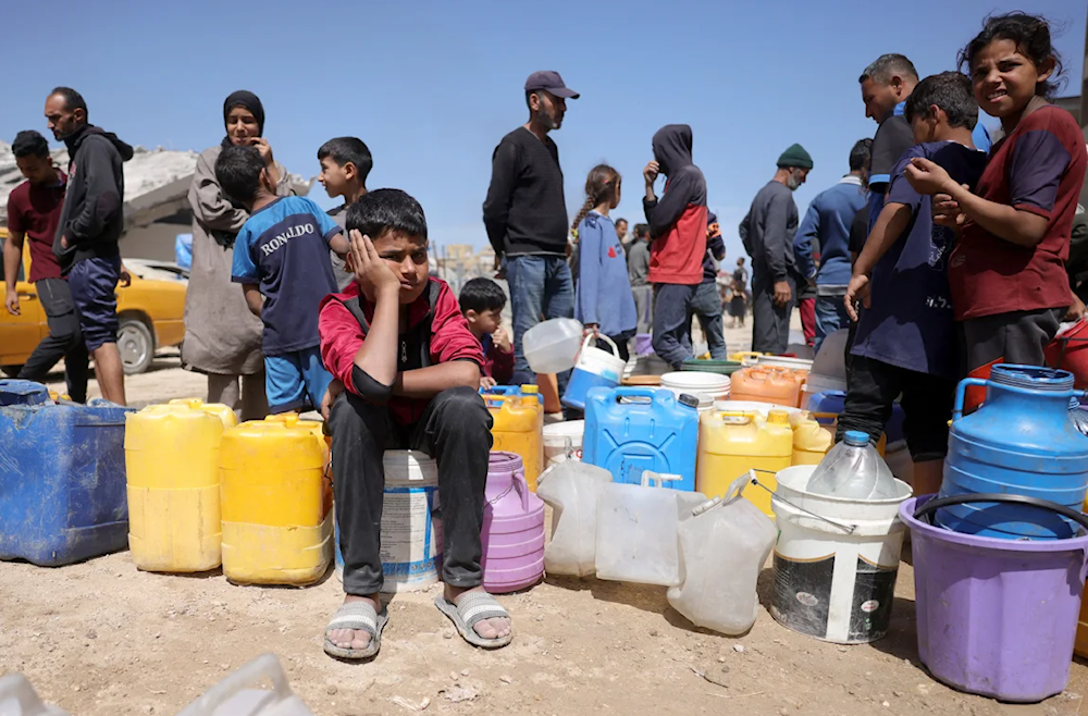 فلسطينيون ينتظرون ما إذا كان بإمكانهم الحصول على المياه في مخيم للنازحين في مدينة غزة - 20 أيار/مايو 2025 (AFP)