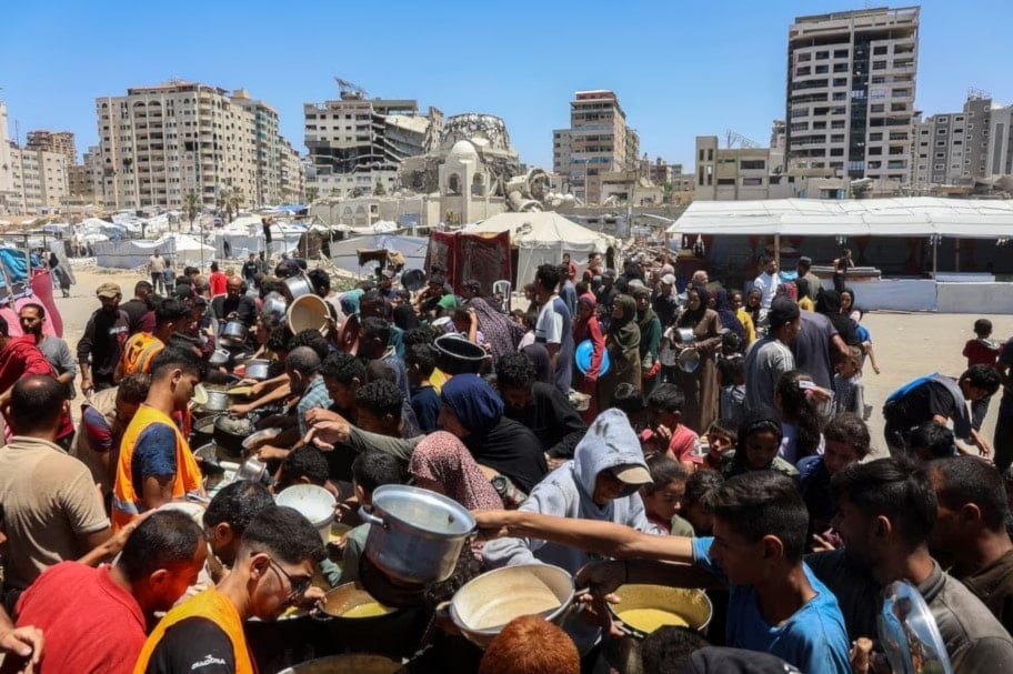 فلسطينيون ينتظرون للحصول على وجبات في نقطة توزيع طعام في مدينة غزة شمالي القطاع. 21 أيار/مايو 2025. (أ. ف. ب)