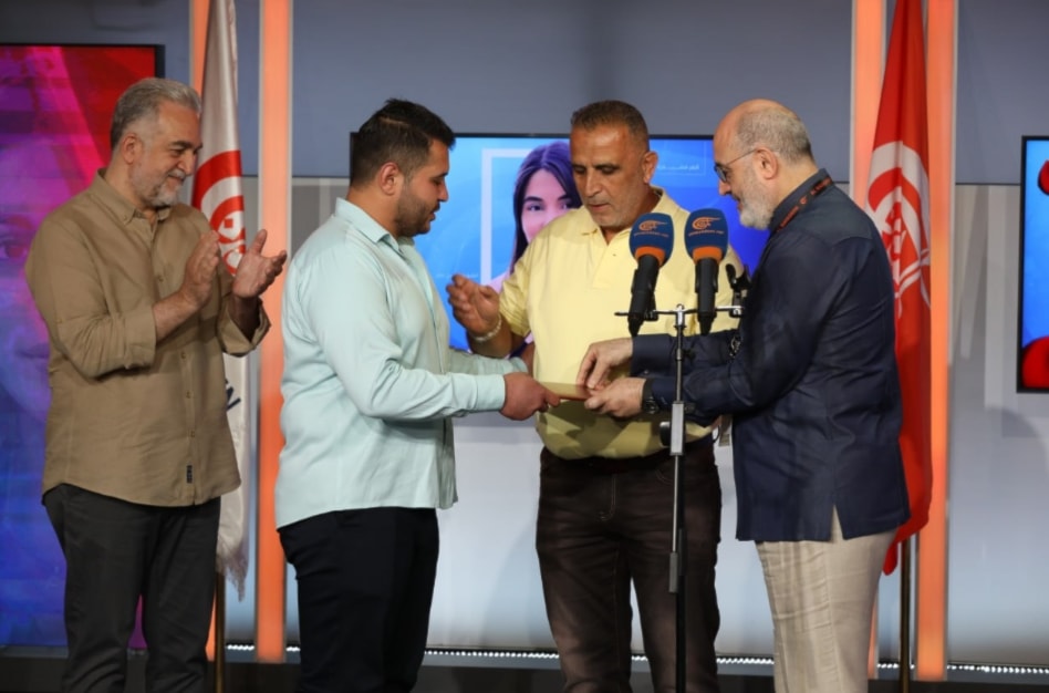 رئيس مجلس إدارة شبكة الميادين يُسلم الطالب عمّار الحمود منحة 