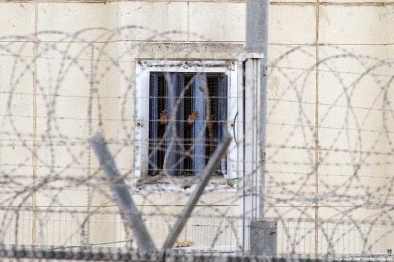 أسرى فلسطينيون يطلّون من خلف الأسلاك الشائكة داخل سجون الاحتلال الإسرائيلي 