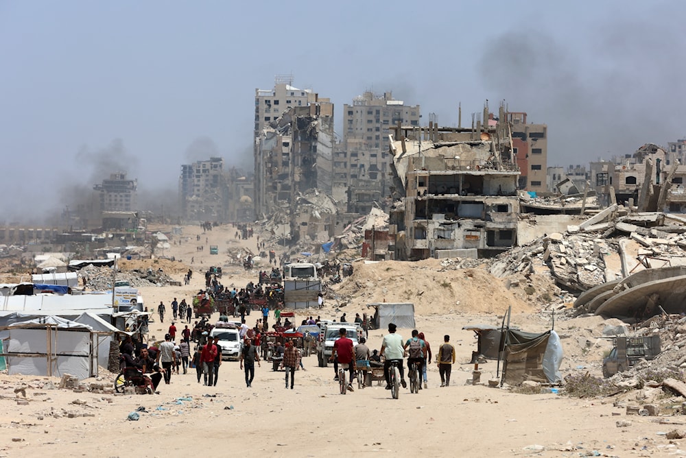 فلسطينيون ينقلون أمتعتهم أثناء توجههم من شمال قطاع غزة باتجاه الجنوب، على طول طريق الرشيد الساحلي - 25 أيار/مايو 2025 (أ ف ب)