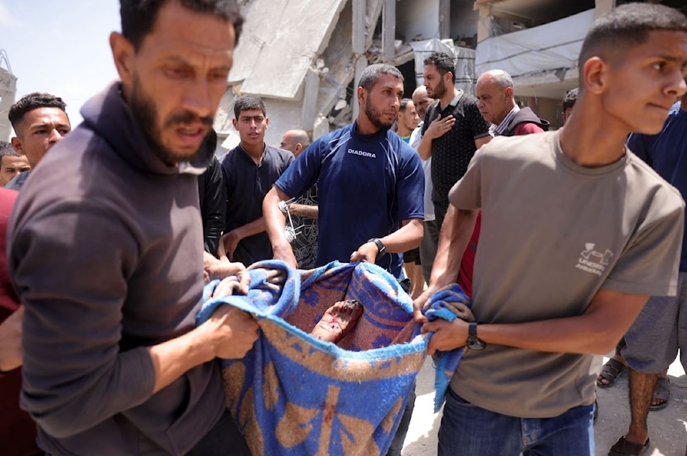 فلسطينيون يحملون جثمان شهيد في غارة إسرائيلية على حي الصفطاوي غربي جباليا شمالي قطاع غزة - 27 أيار/مايو 2025 (أ ف ب)