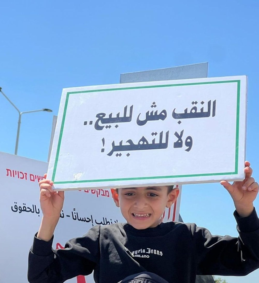 طفل يحمل لافتة كُتب عليها 