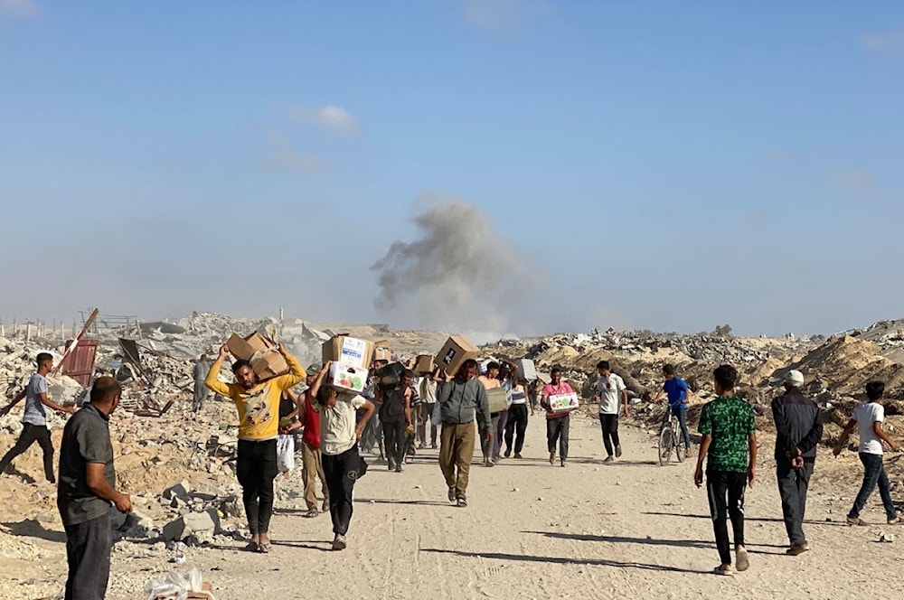 نازحون فلسطينيون يتسلمون طروداً غذائية غربي رفح جنوبي قطاع غزة وسط حصار إسرائيلي خانق - 27 أيار/مايو 2025 (أ ف ب)