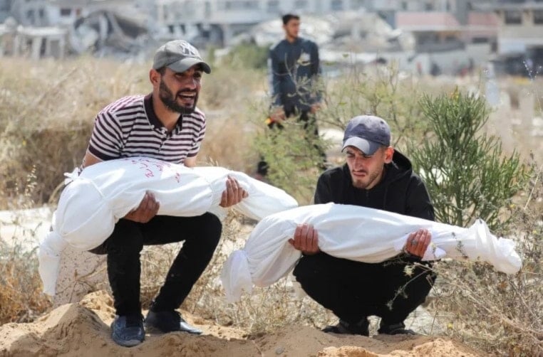 فلسطينيان يحملان جثماني طفلين من عائلة العرابيد قُتلا في الغارات الإسرائيلية. غزة. 28 أيار/مايو 2025 (رويترز)