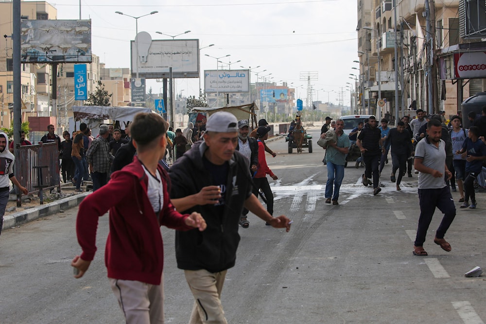 فلسطينيون يبتعدون عن نقطة توزيع المساعدات بالقرب من حاجز 