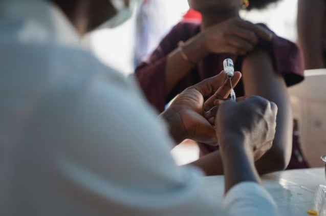 مسؤول صحي نيجيري يستعد لإعطاء لقاح إمبوكسي لامرأة، في المركز الطبي الفيدرالي في أبوجا في نيجيريا (رويترز)
