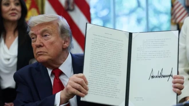 الرئيس الأميركي دونالد ترامب يحمل أمراً تنفيذياً موقعاً في المكتب البيضاوي بالبيت الأبيض 