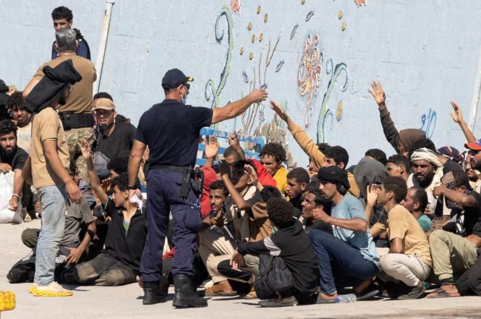 مهاجرون وصلوا حديثاً إلى قاعة بلدية في بلدة أجيا في جزيرة كريت في اليونان (رويترز)