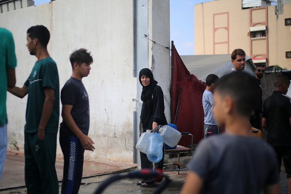 نازحون فلسطينيون يحصلون على المياه من نقطة توزيع في مخيم النصيرات للاجئين وسط قطاع غزة - 10 تموز/يوليو 2025