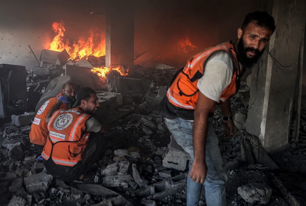 الدفاع المدني الفلسطيني يعمل في مبنى قصفه الاحتلال الإسرائيلي في مدينة غزة (AFP)