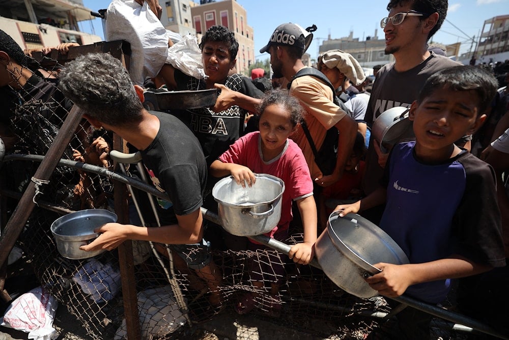 فلسطينيون يتجمعون عند نقطة توزيع طعام في مخيم النصيرات للاجئين وسط قطاع غزة - 19 تموز/يوليو 2025 (أ ف ب)