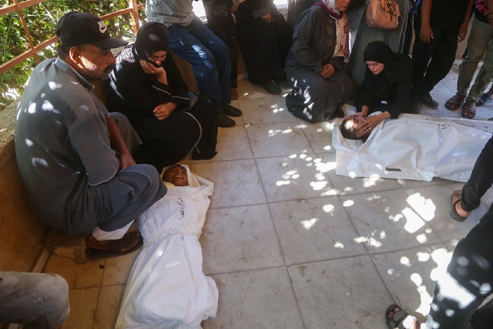 والدا الطفل عبد الجواد الغلبان (14 عاماً)، المستشهد من جراء التجويع، ينعيانه بينما ينعى آخرون جثمان شهيد ارتقى في قصف إسرائيلي في مستشفى ناصر في خان يونس (22 تموز/يوليو 2025 - أ ف ب)