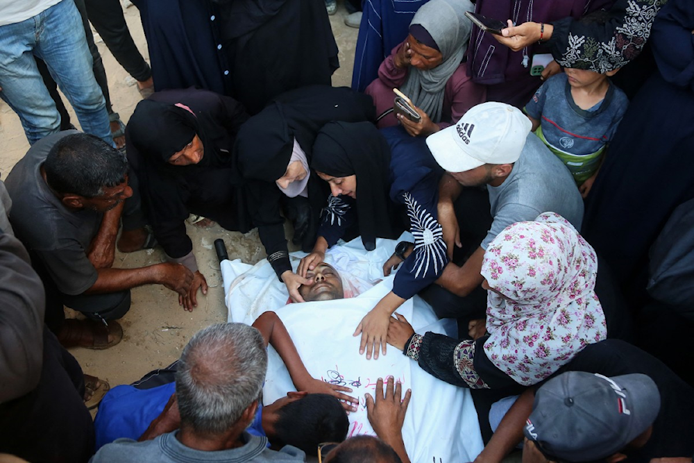 عائلة فلسطينية فوق جثمان أحد أبنائها في مستشفة ناصر بغزة اليوم (أ ف ب)