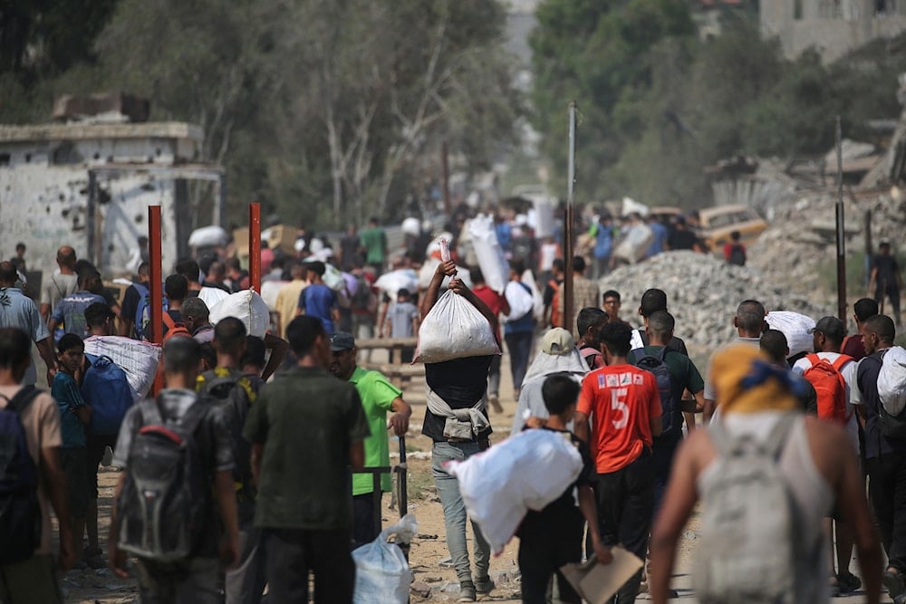 نازحون فلسطينيون يحملون طروداً غذائية ومواد أخرى في نقطة توزيع مساعدات في ما يسمى 