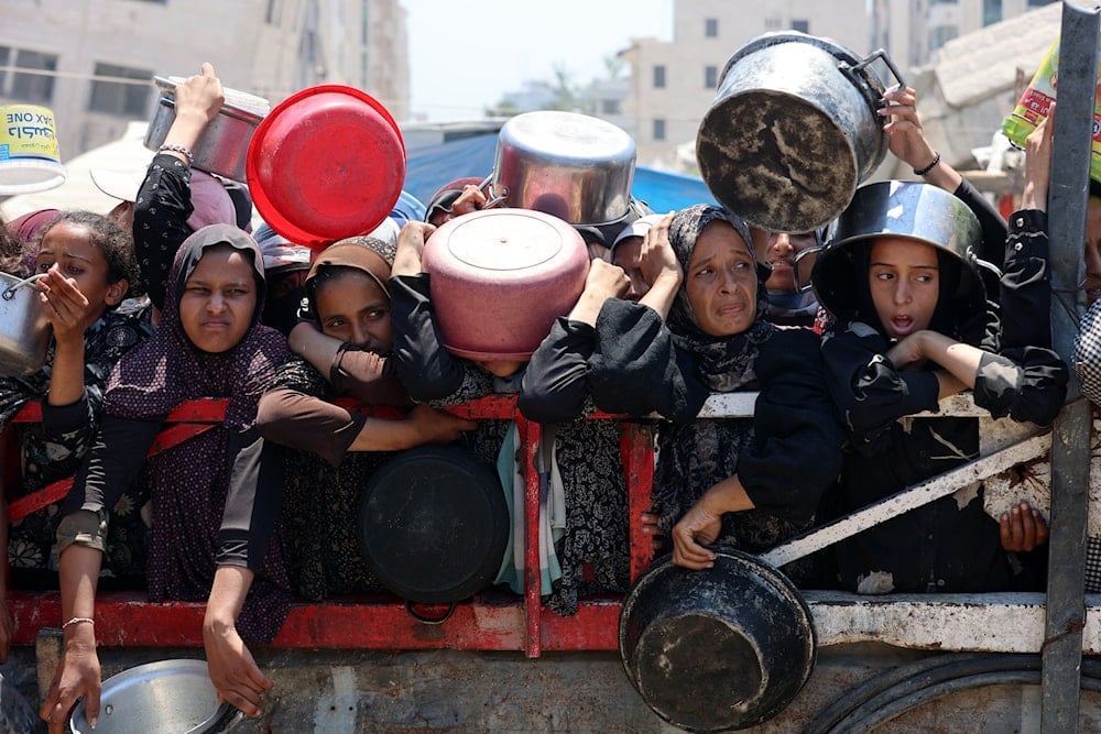 فلسطينيون يتجمعون عند نقطة توزيع حساء العدس في مدينة غزة شمالي قطاع غزة - 27 تموز/يوليو 2025 (أ ف ب)