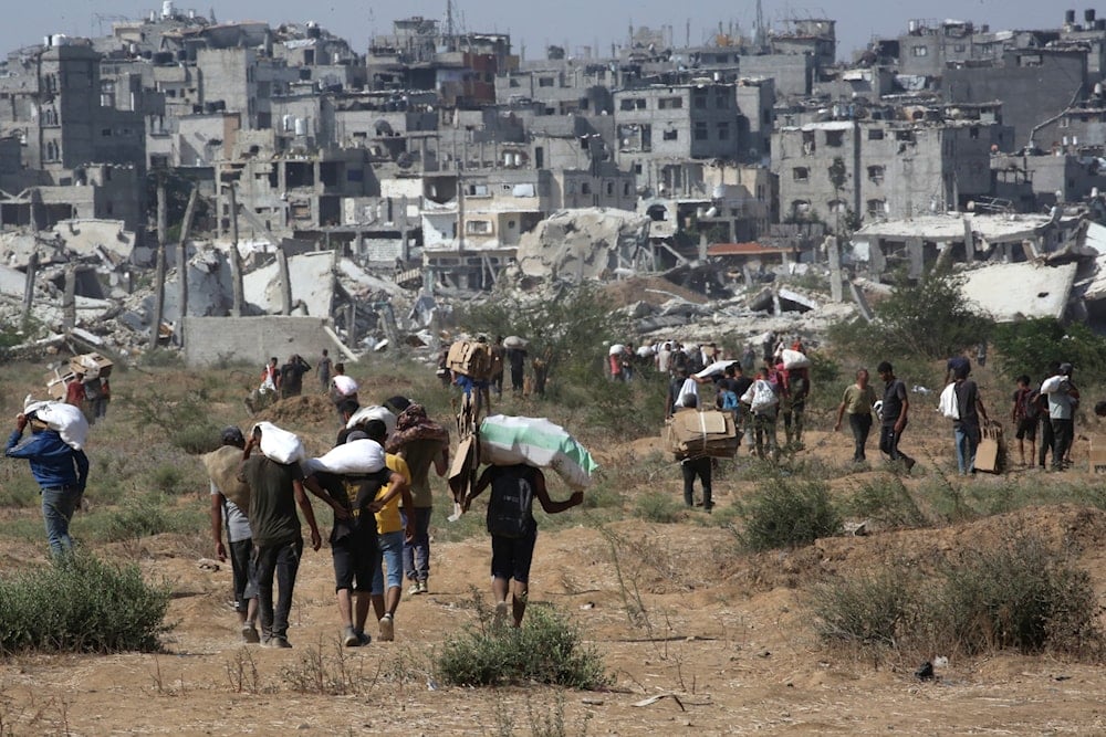 أشخاص يحملون مساعدات تمكنوا من الحصول عليها في أحد نقاط توزيعها وسط قطاع غزة (AFP)