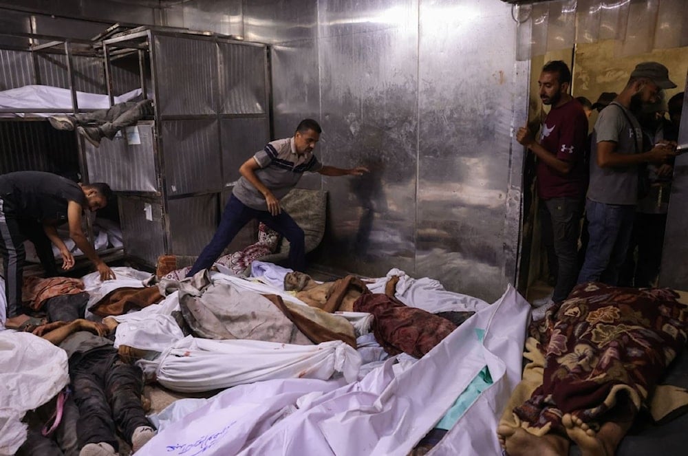 فلسطينيون يتفقدون شهداء ارتقوا أثناء انتظارهم المساعدات الإنسانية في مشرحة مستشفى الشفاء بمدينة غزة - 31 تموز/يوليو 2025 (أ ف ب)